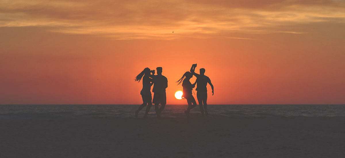 Fire venner som danser foran en solnedgang