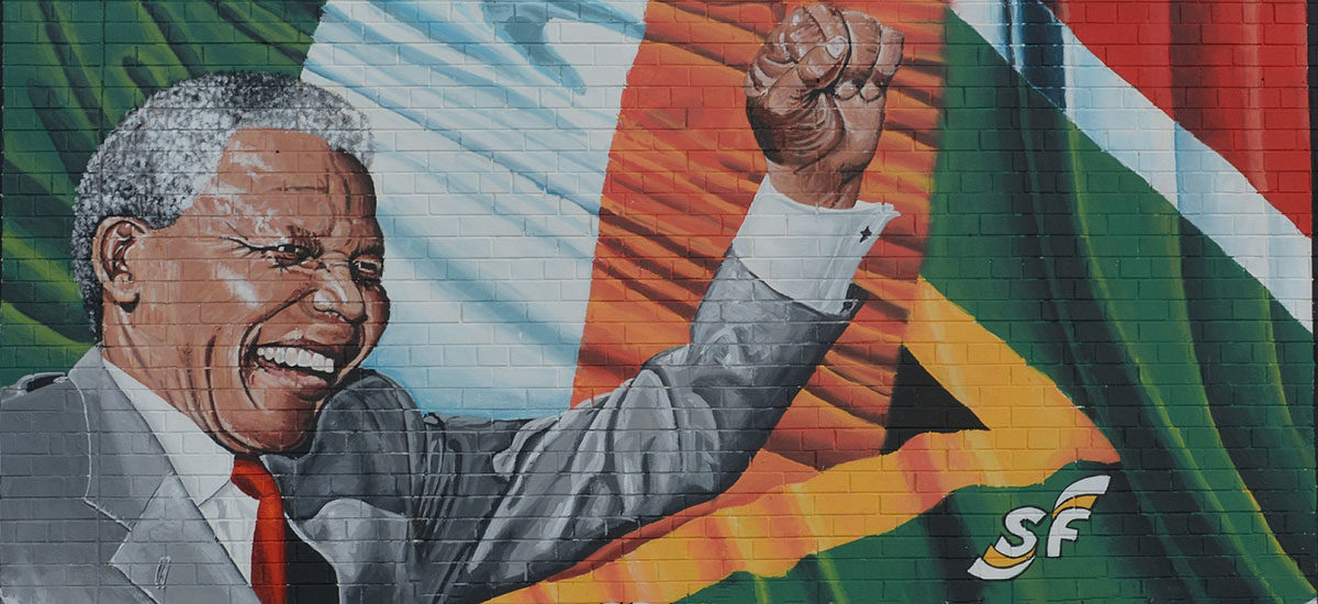 Veggmaleri som avbilder en smilende Nelson Mandela med hevet knyttneve med det Sør-Afrikanske flagget i bakgrunnen