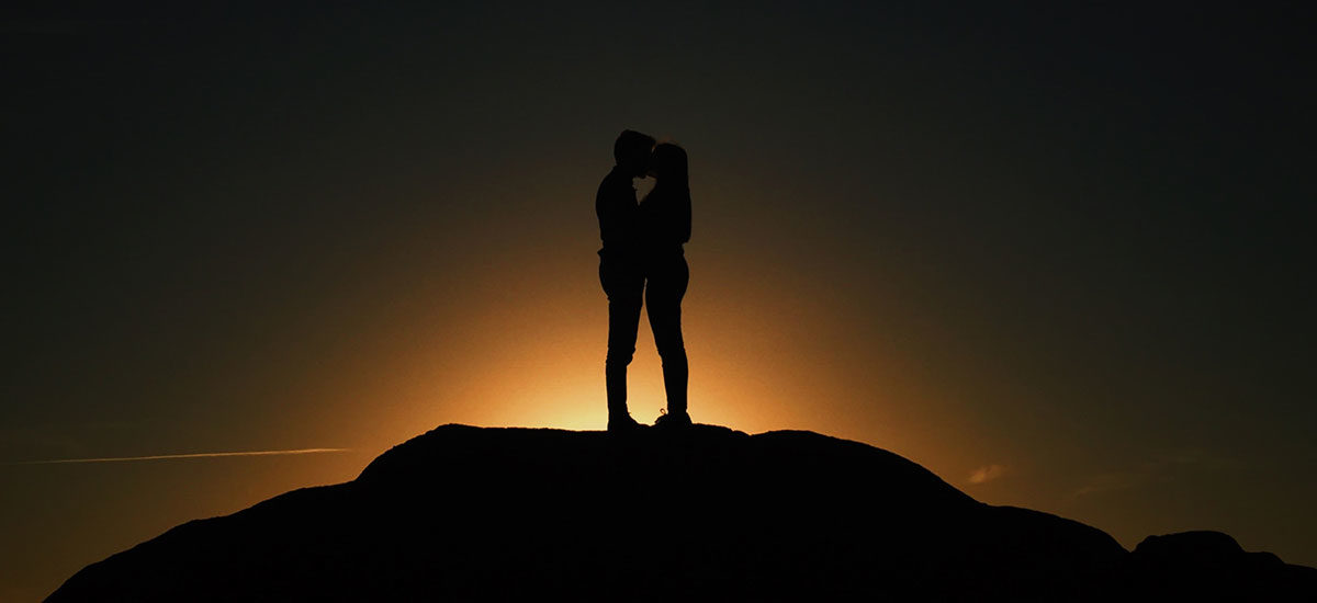 To personer som kysser foran soloppgangen