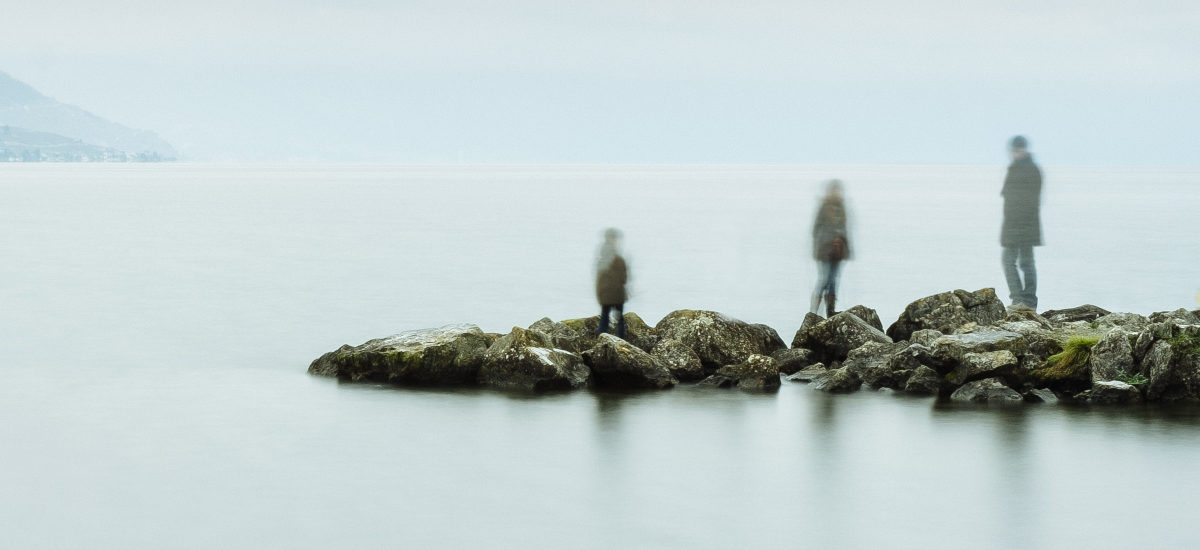 Tre personer står på et berg ved havet