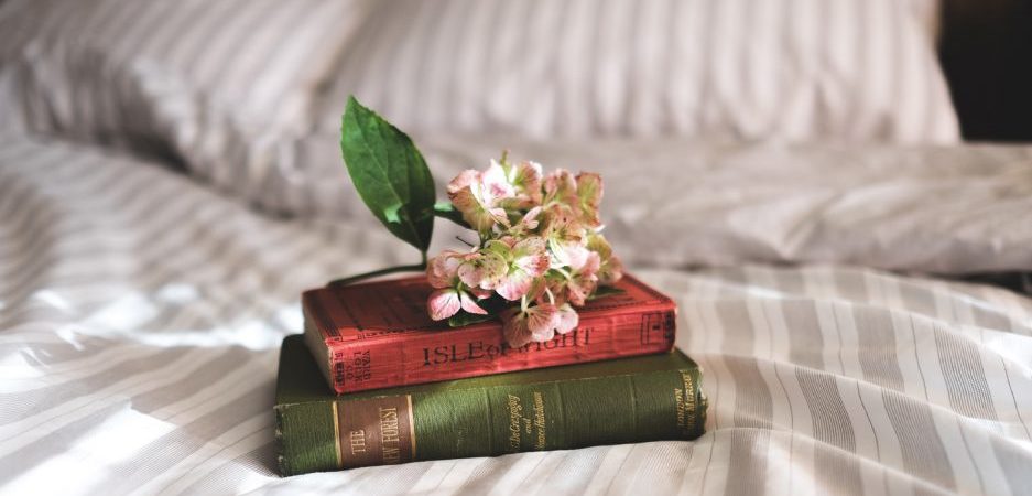 Bøker på en seng med blomst