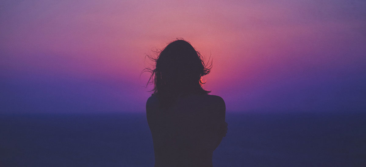 Kvinne i sterk kontrast med lilla og rosa himmel i bakgrunnen