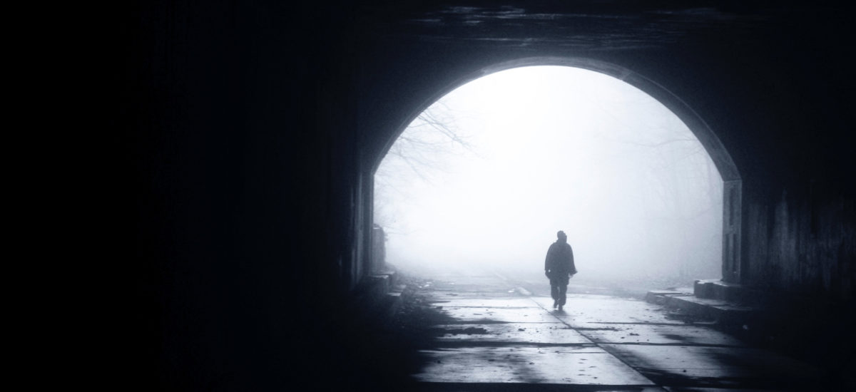 Mann går igjennom en tunell med en tåkefylt ende