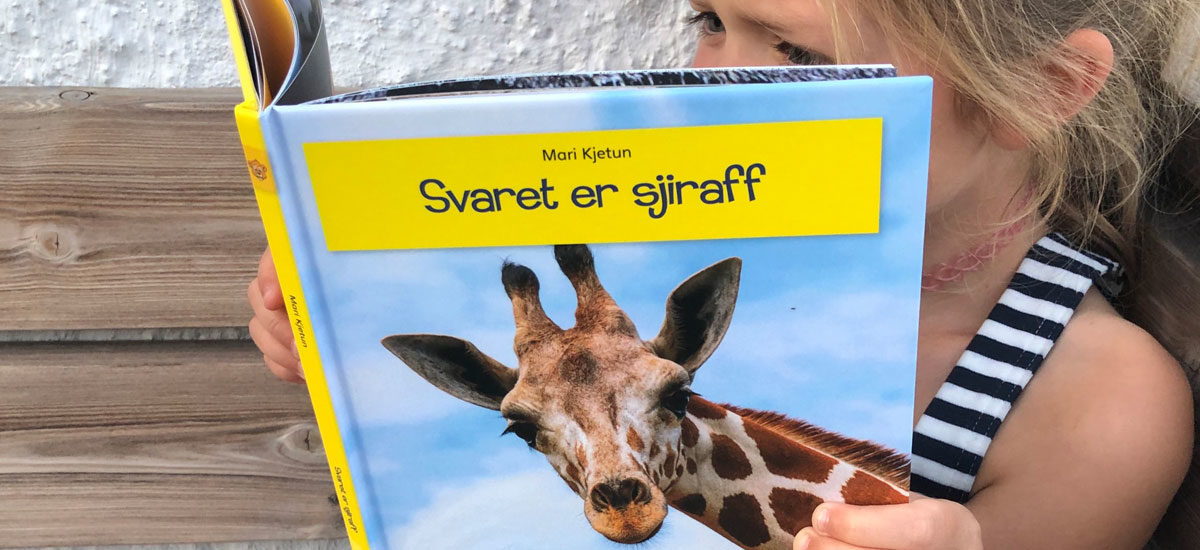 Foto av jente på 6 år som leser lettlest-boka "Svaret er giraff" i serien Leseløve