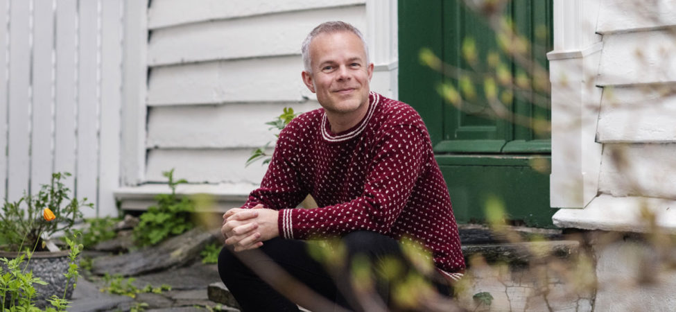 Portrettfoto av forfatter Tore Renberg hvor han sitter på en trapp i Gamle Stavanger