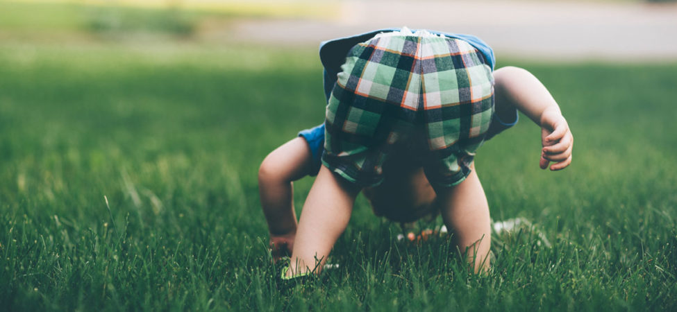 Foto av en liten gutt som bøyer seg ned i gresset. Illustrasjon til dikt av Morten Wintervold