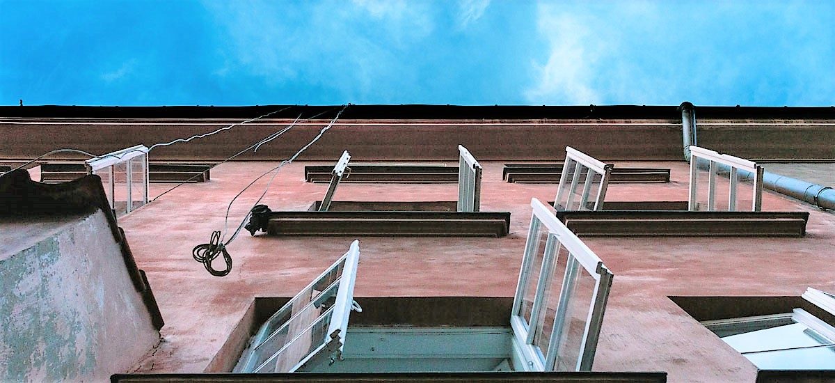 Foto av husvegg med åpne vinduer sett nedenfra, blå himmel
