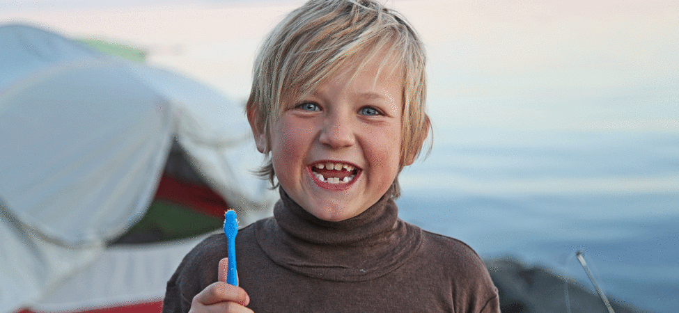 Gutt med tannbørste utenfor telt
