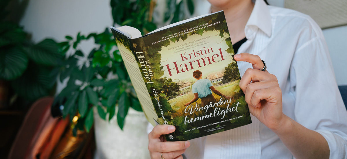 Kvinne holder boka "Vingårdens hemmelighet" av Kristin Harmel