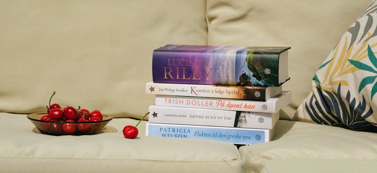 Foto av en bunke underholdningsromaner på en utesofa, sommerlige omgivelser