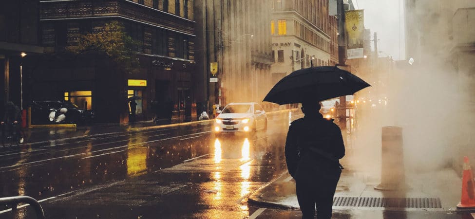 Mann med paraply fotografert bakfra i røykfylt gate