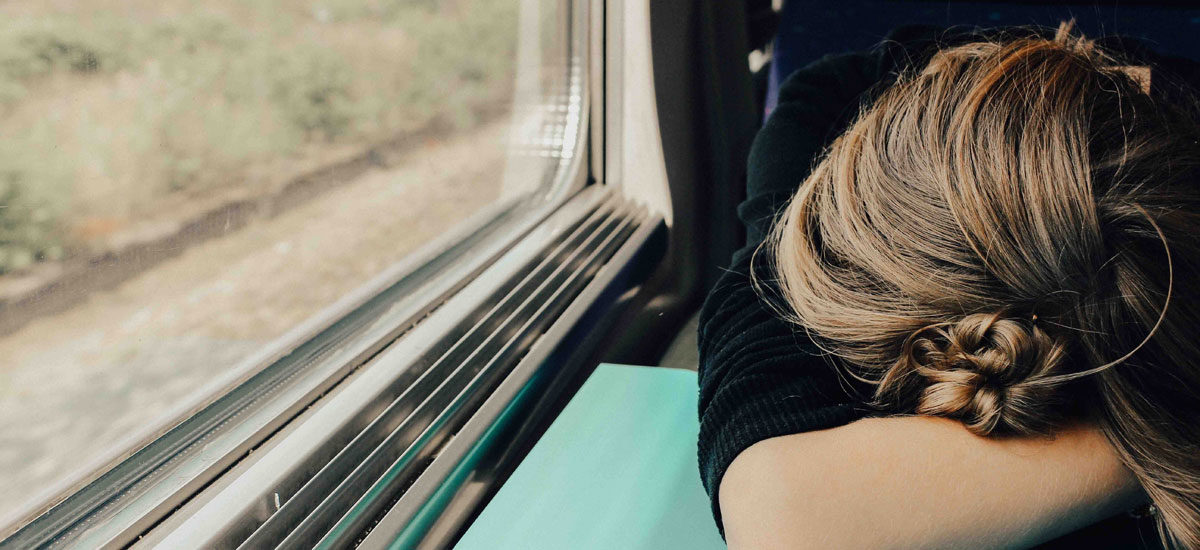 Foto av kvinne som ligger med hodet på bordet på toget