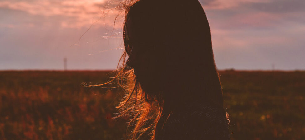 Foto av en kvinne i profil, solnedgang bak