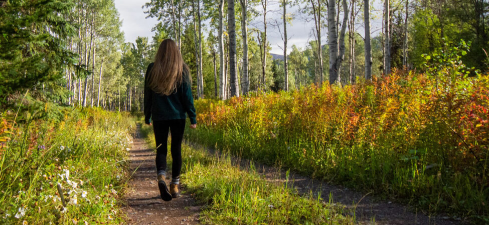 Foto av kvinne som går langs en skogsvei