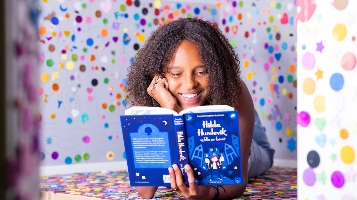 Melaninrik jente som leser bok og smiler