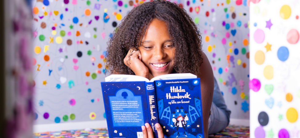Melaninrik jente som leser bok og smiler