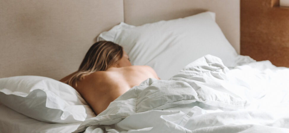 Foto av kvinne som ligger alene i sengen.