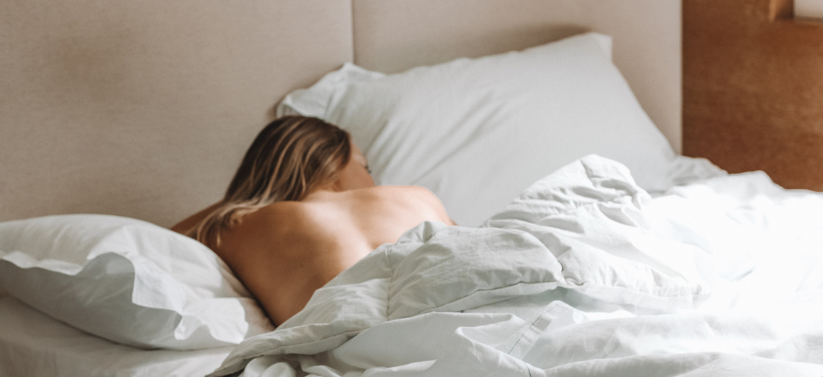 Foto av kvinne som ligger alene i sengen.