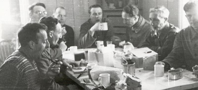 Foto i sort/hvitt av menn rundt et frokostbord
