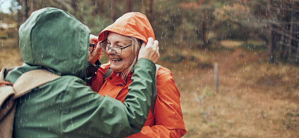 Foto av to glade eldre folk i regnvær