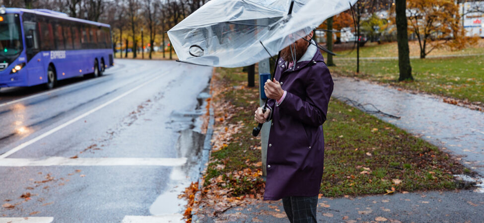 Mann som står i høstregn med ødelagt paraply. Illustrasjon til diktet "November" av Inger Hagerup