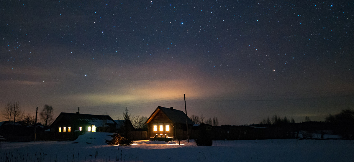 Foto av hus med lys i på mørkt jorde om vinteren.